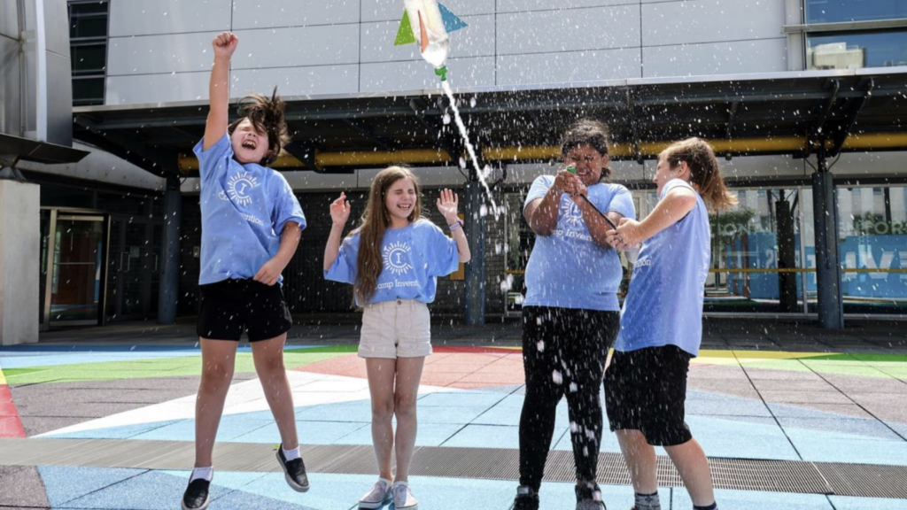 National Inventors Hall of Fame Foundation. Image shows children celebrating as a soda rocket launches.