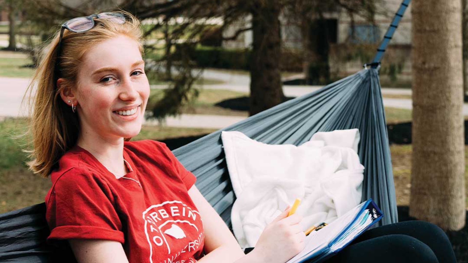 Otterbein University. Image shows a girl smiling in a hammock.