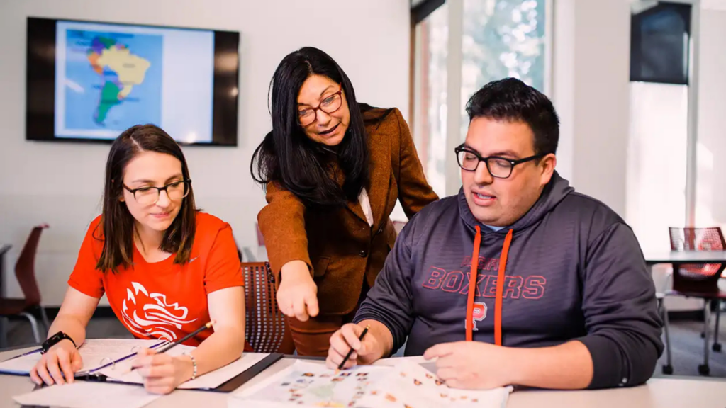 Pacific University. Image shows teacher pointing something out to college students during class.