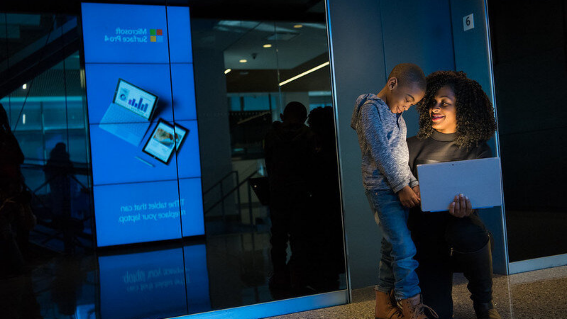Partners in Achieving Community Transformation. Image shows a mom showing her son something on her computer.