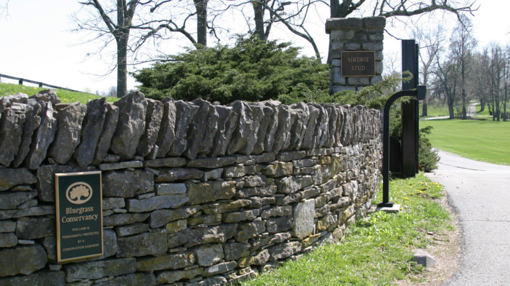 Bluegrass Land Conservancy. Image shows historical stone fence with Bluegrass Conservancy marker at the front.