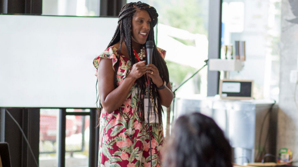 Women’s Funding Network. Image shows a woman speaking in front of a crowd.