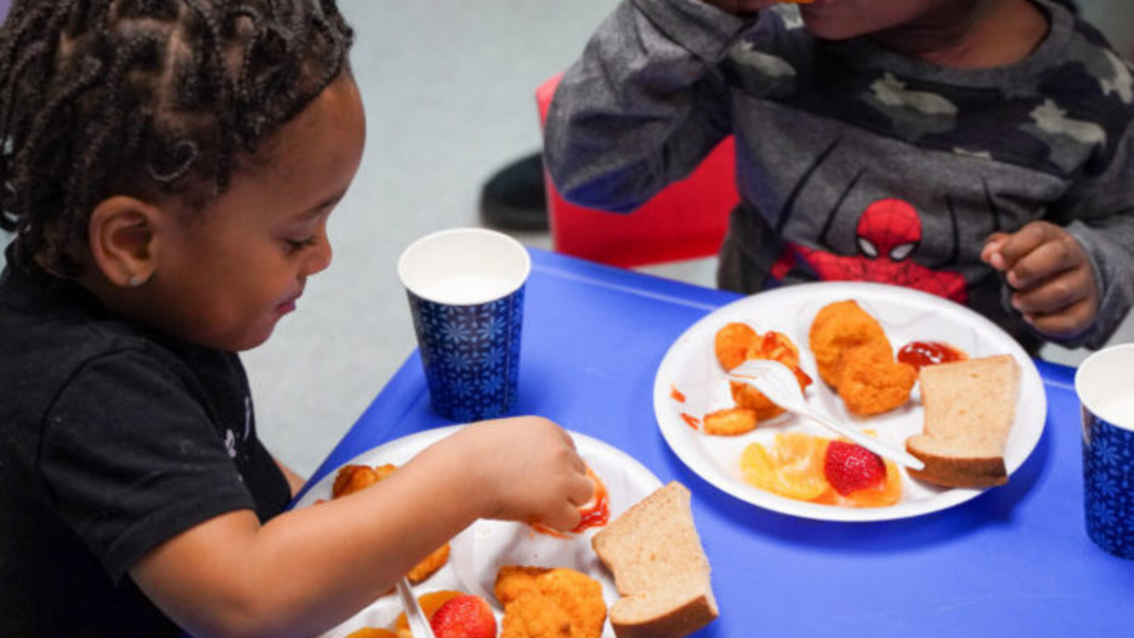 Children’s Hunger Alliance. Image shows a child smiling and eating.