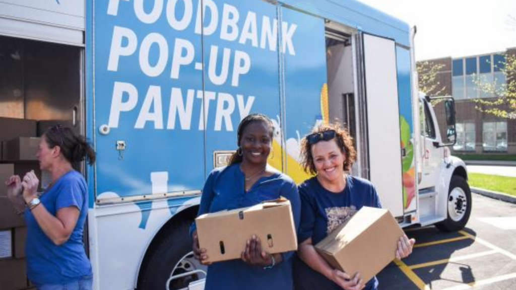 Akron-Canton Regional Foodbank. Image shows two women holding boxes of food outside of the foodbank pop-up pantry.