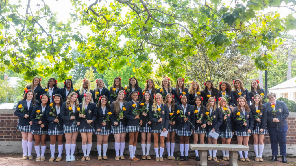 Columbus School for Girls. Image shows girls in uniform, smiling, and holding yellow roses.