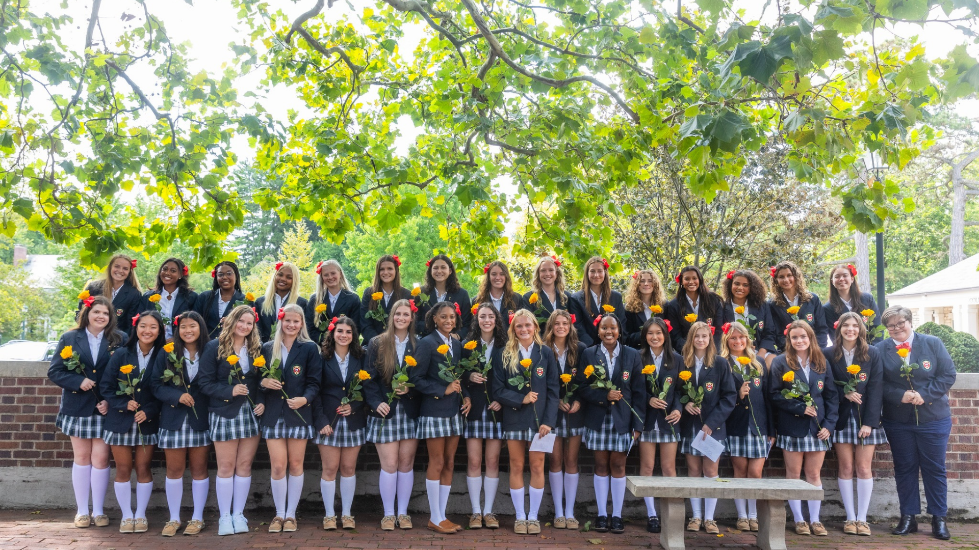 Columbus School for Girls. Image shows girls in uniform, smiling, and holding yellow roses.
