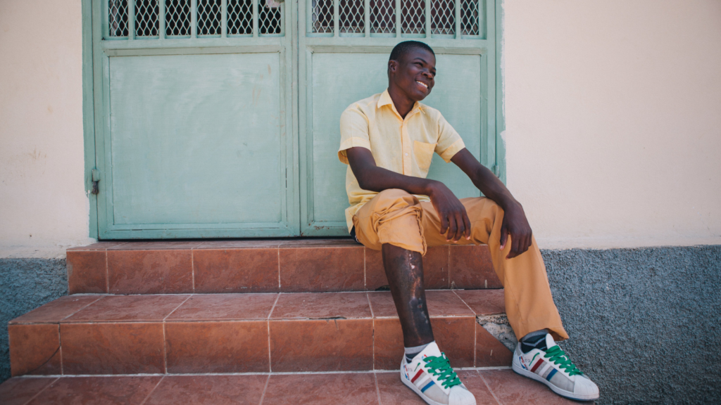 Healing Art Missions. Image shows teen smiling on a porch stoop.