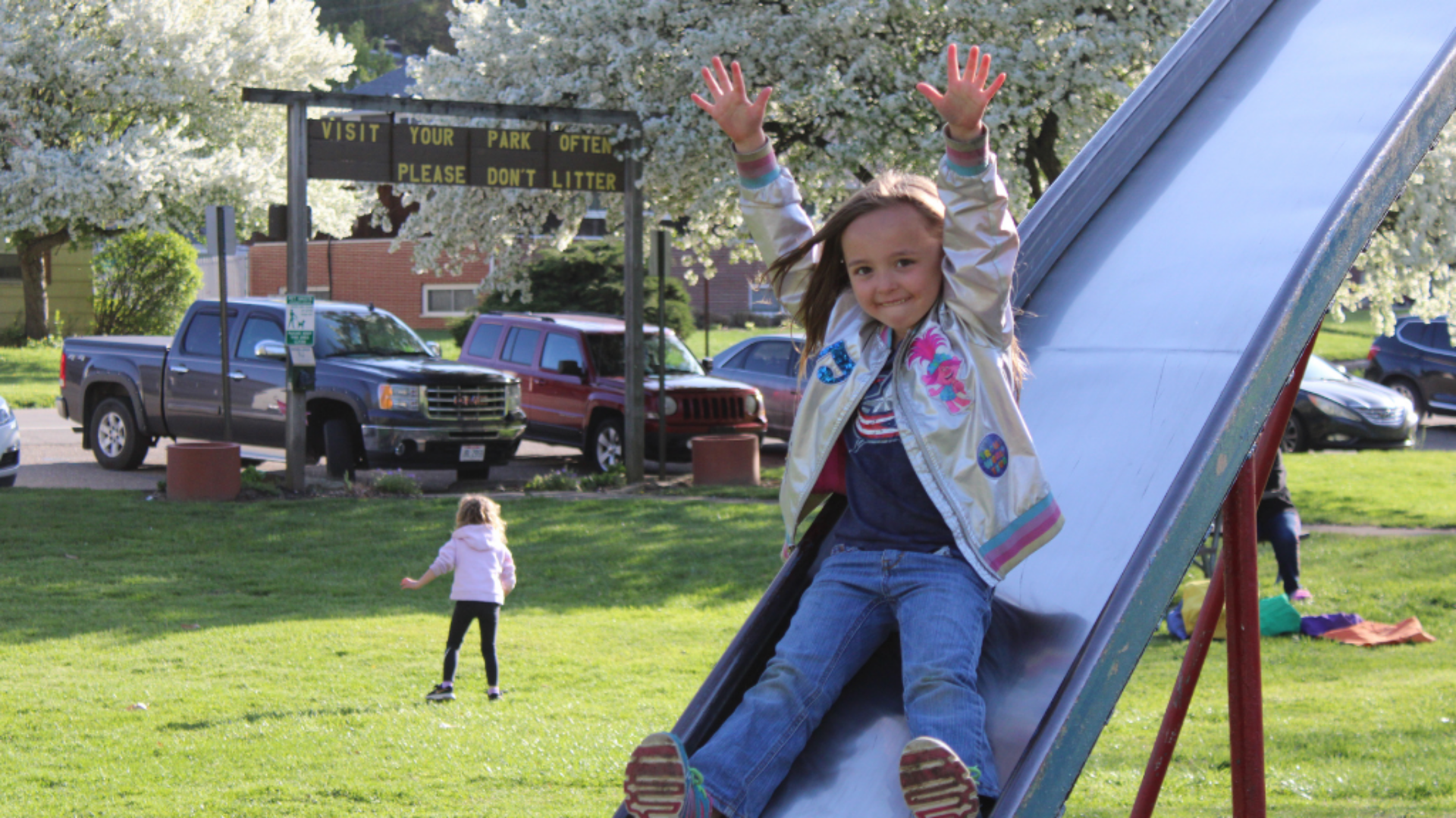 Hocking Athens Perry Community Action. Image shows little girl sliding down a slide on a playground.
