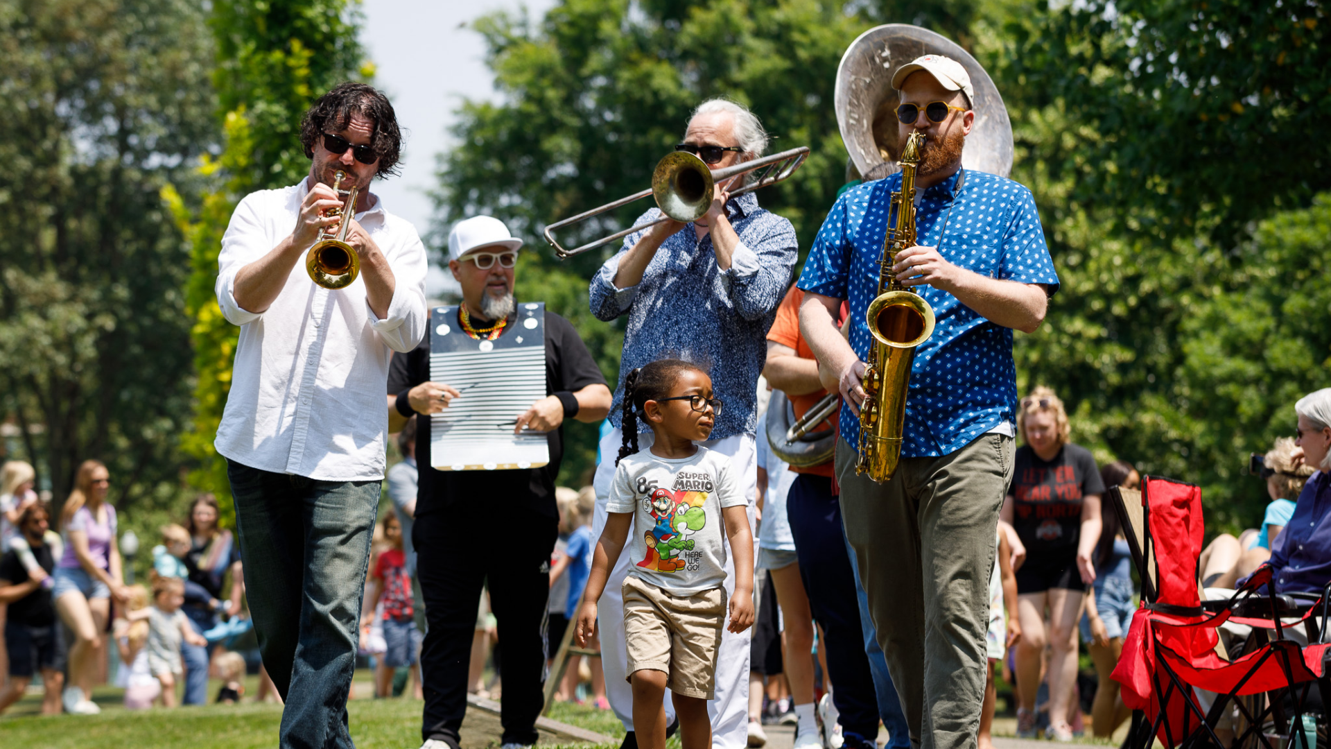 Jazz Arts Group. Image shows a jazz parade with musicians in a park.