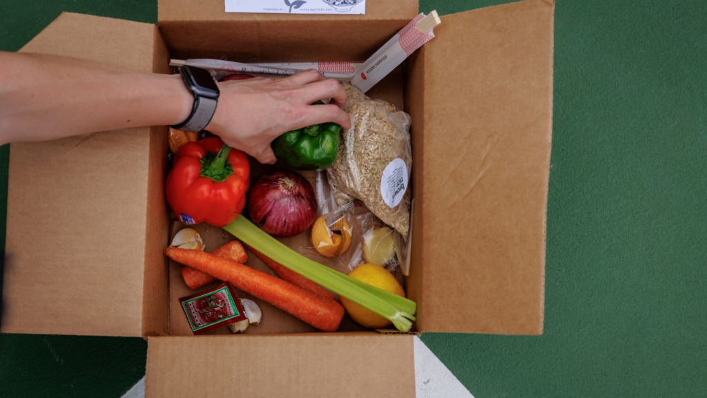 Local Matters. Image shows a hand reaching into a box of food.