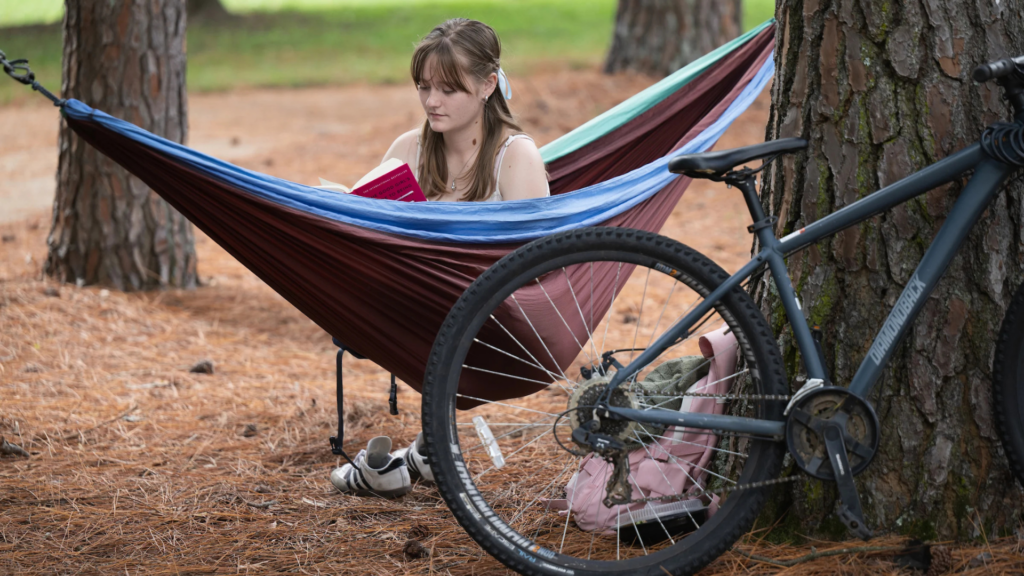 Lyon College. Image shows a student reading in a hammock.