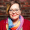 Taylor Boulware, PhD. Taylor is smiling wearing glasses, a rainbow scarf, and red sweater.